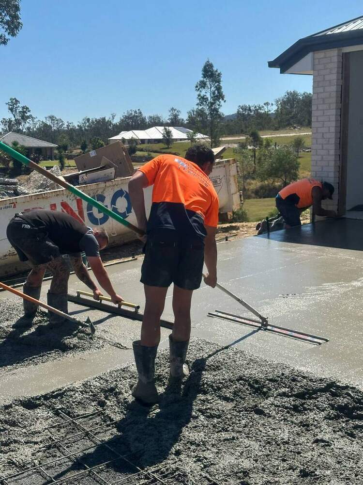 Crew pouring and screeding concrete slab